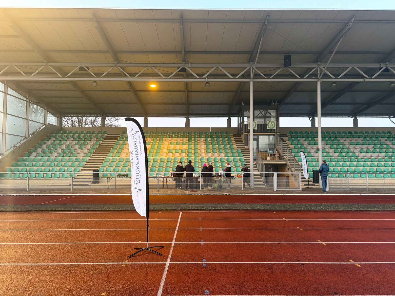 Aufbau des Weihnachtslaufs 2025 im Stadion Im Blumengarten: Helferinnen und Helfer, Tombola-Tisch und Vereinsfahnen im Morgennebel