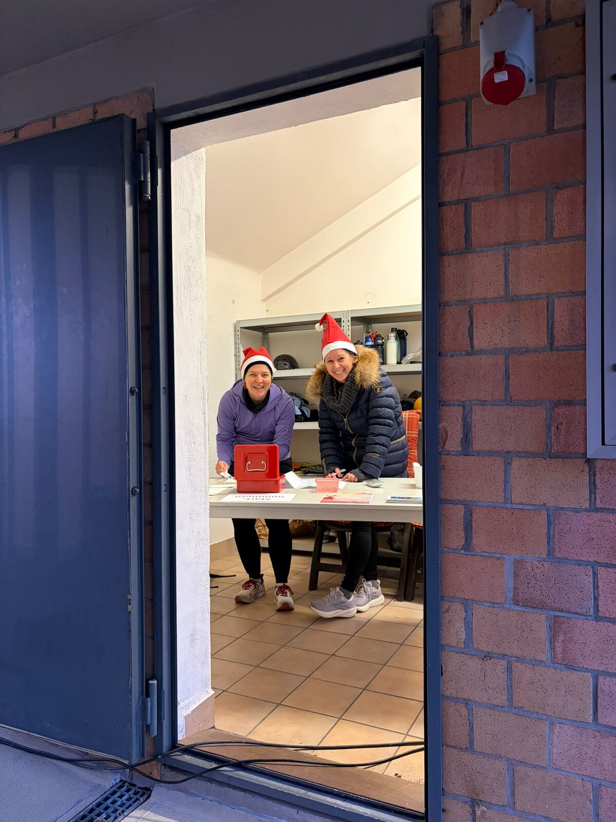 Aufbau des Weihnachtslaufs 2025 im Stadion Im Blumengarten: Helferinnen und Helfer, Tombola-Tisch und Vereinsfahnen im Morgennebel