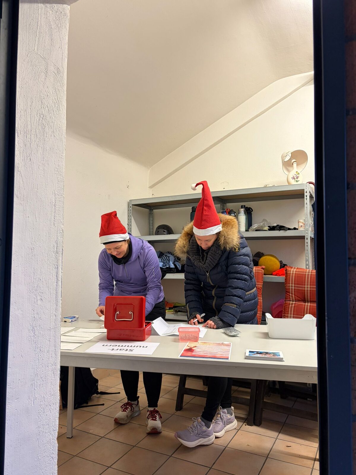 Aufbau des Weihnachtslaufs 2025 im Stadion Im Blumengarten: Helferinnen und Helfer, Tombola-Tisch und Vereinsfahnen im Morgennebel