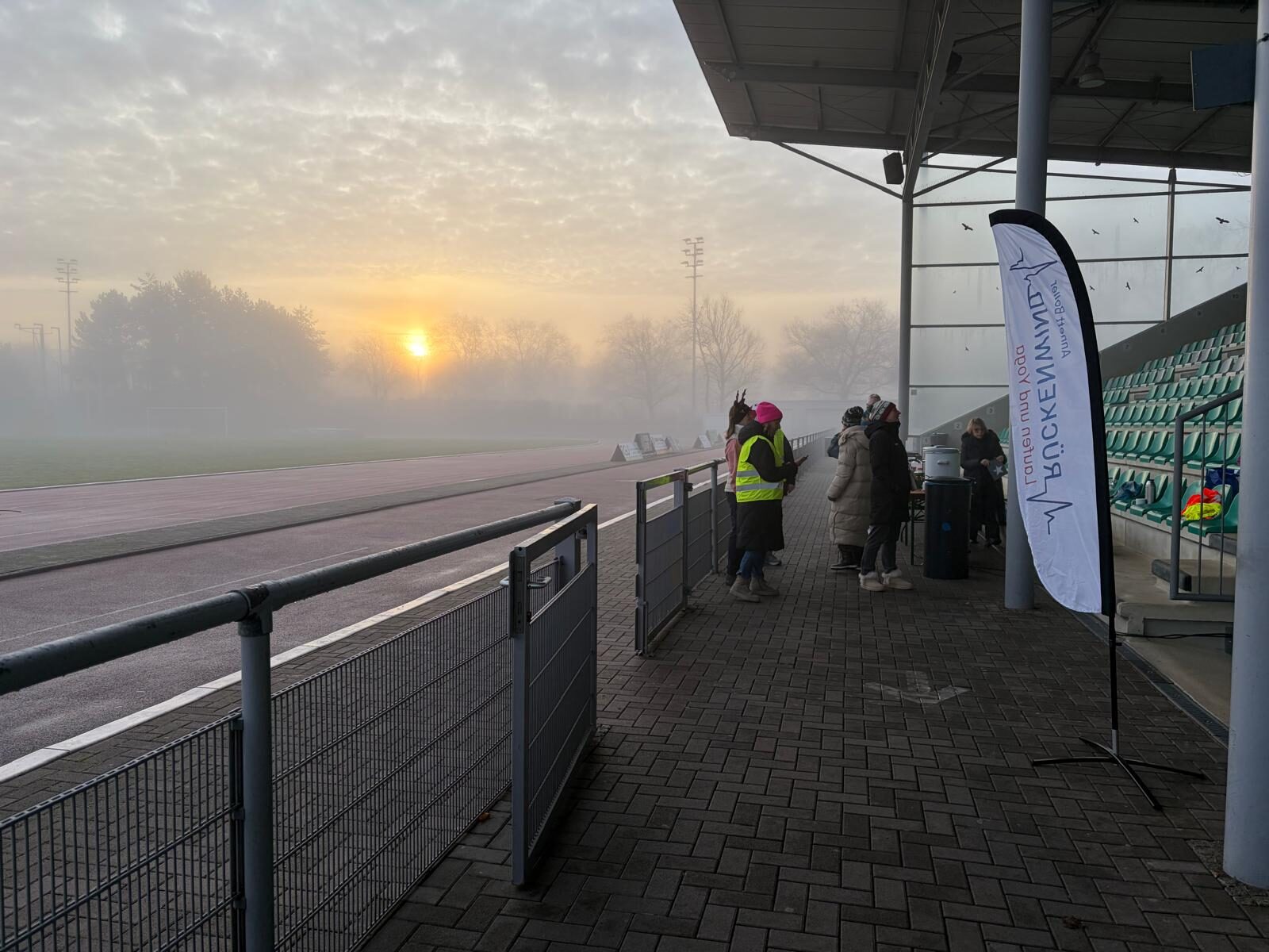Aufbau des Weihnachtslaufs 2025 im Stadion Im Blumengarten: Helferinnen und Helfer, Tombola-Tisch und Vereinsfahnen im Morgennebel