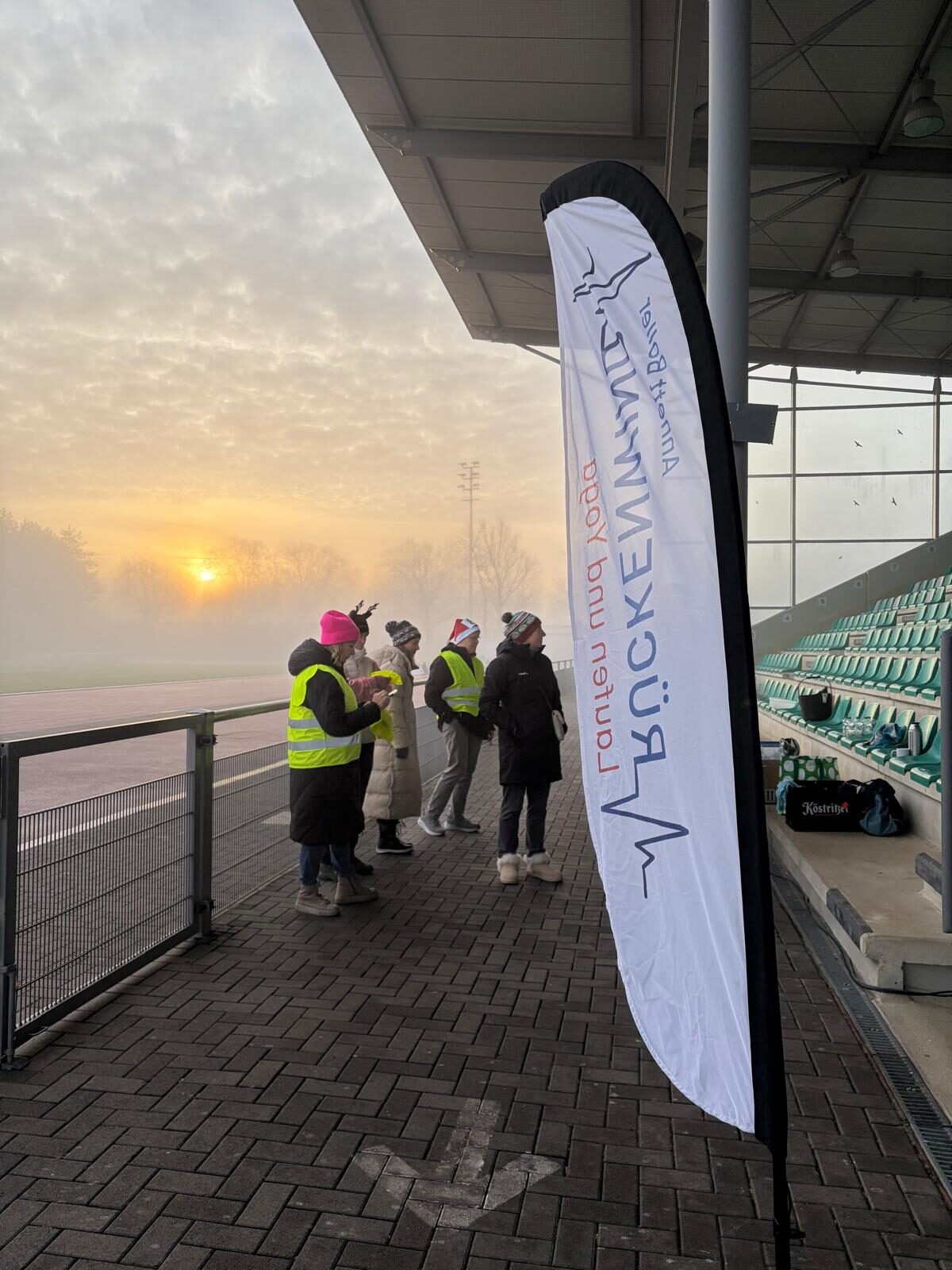 Aufbau des Weihnachtslaufs 2025 im Stadion Im Blumengarten: Helferinnen und Helfer, Tombola-Tisch und Vereinsfahnen im Morgennebel